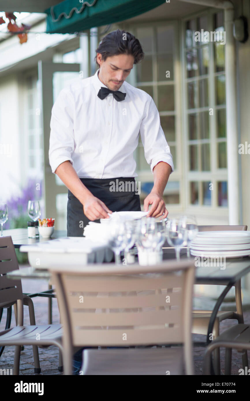 Waiter folding napkins in patio restaurant Stock Photo Alamy