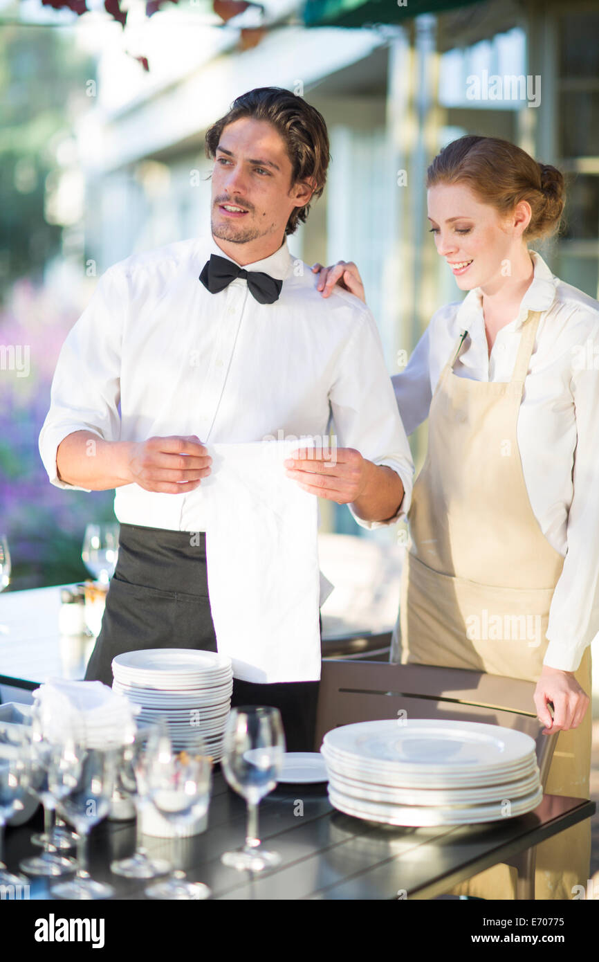 Waiter and waitress setting up tables in patio restaurant Stock Photo