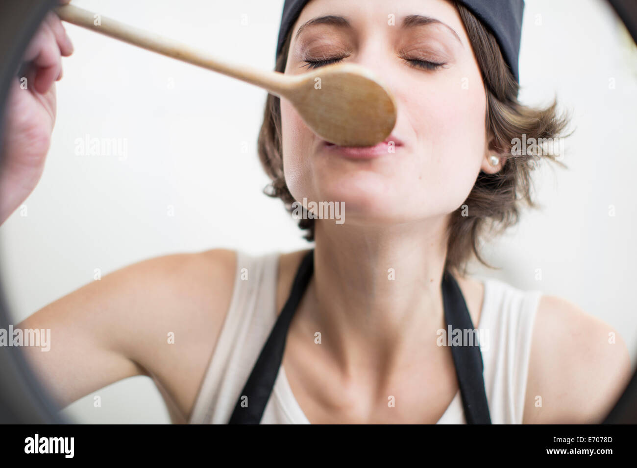 Female chef tasting food from saucepan in commercial kitchen Stock Photo