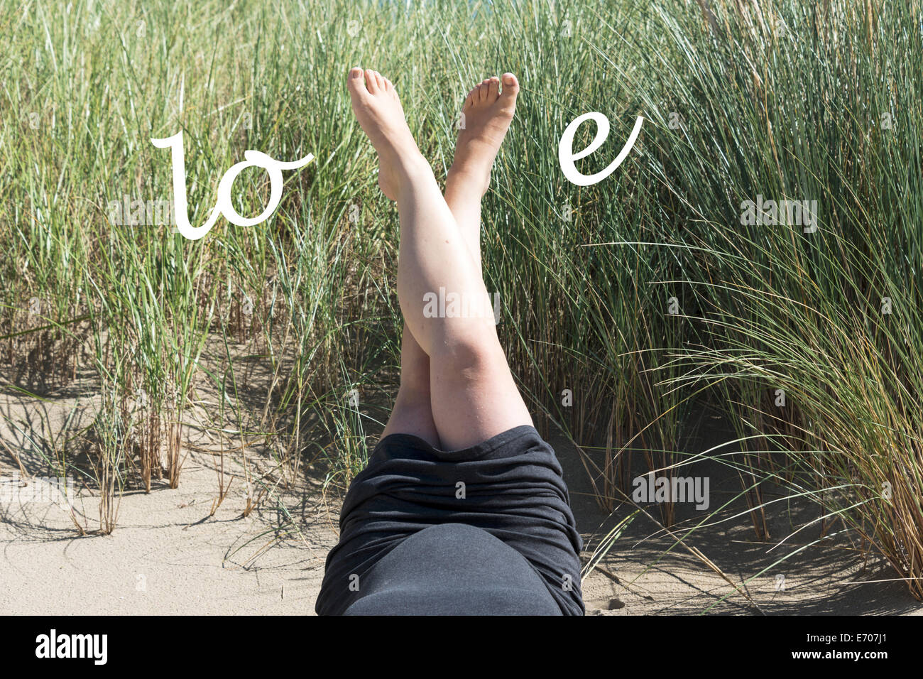 pregnant woman with love letters on her belly in the sand Stock Photo