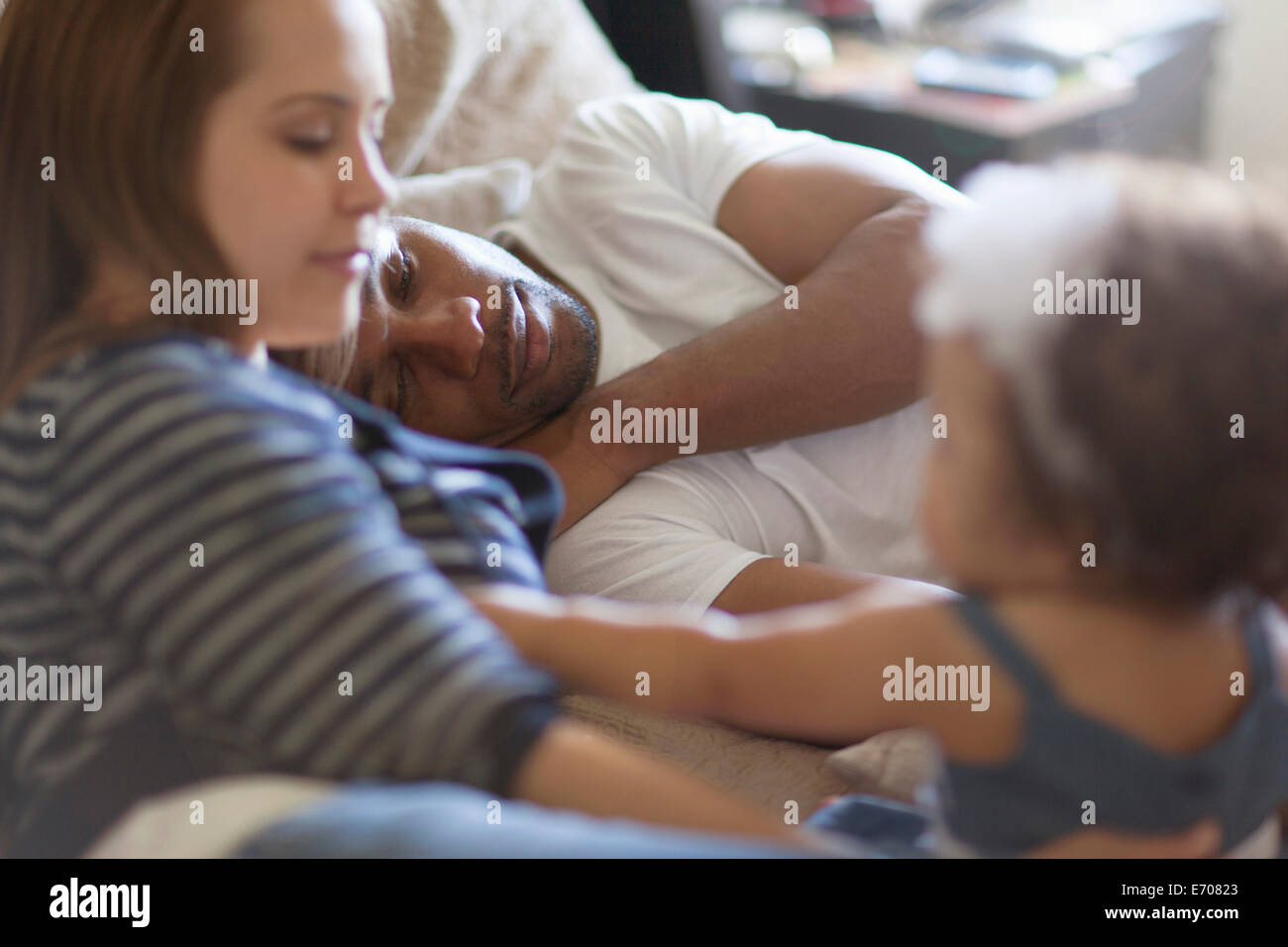 Mother and father lying on bed with baby daughter Stock Photo