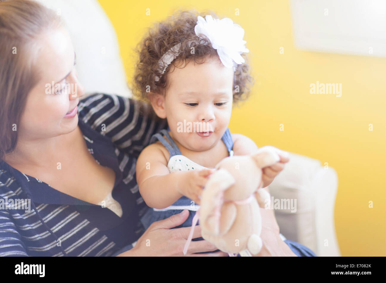 Mother holding baby daughter, playing with soft toy Stock Photo
