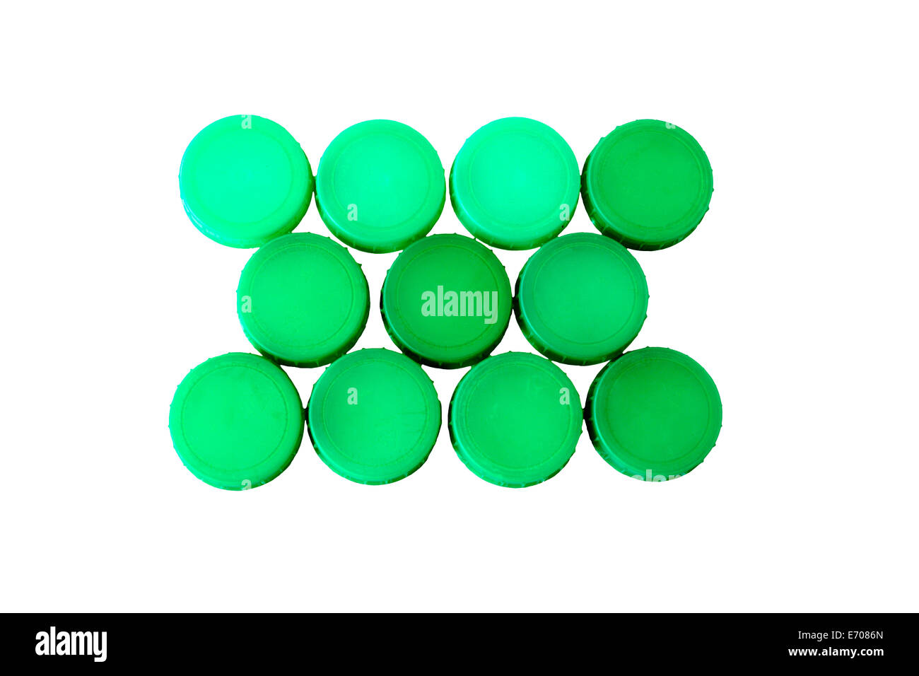 Eleven Green plastic milk bottle tops in neat rows on white background Stock Photo