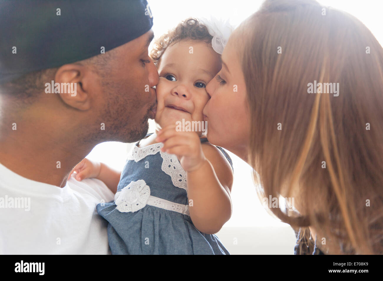 Mother and father kissing young daughter on cheeks Stock Photo