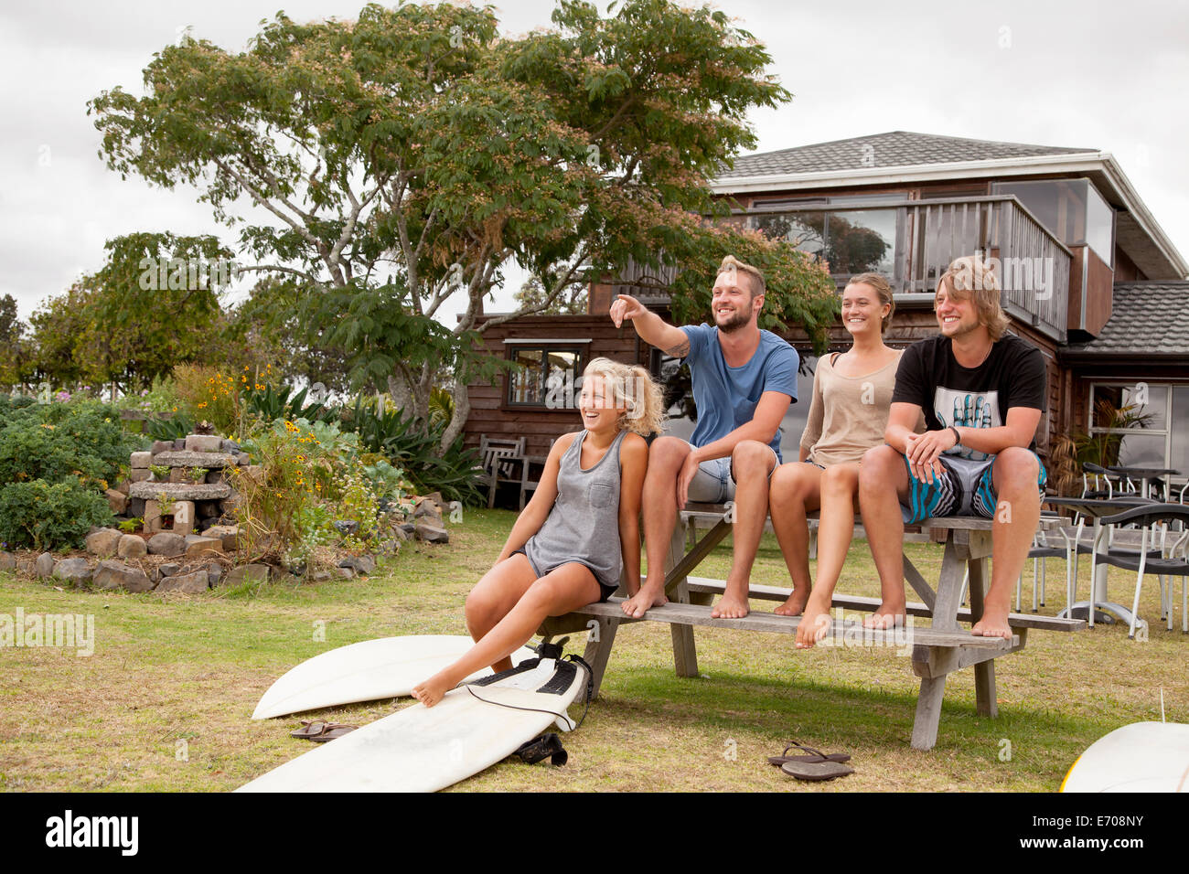 Four surfer friends sitting on picnic bench Stock Photo
