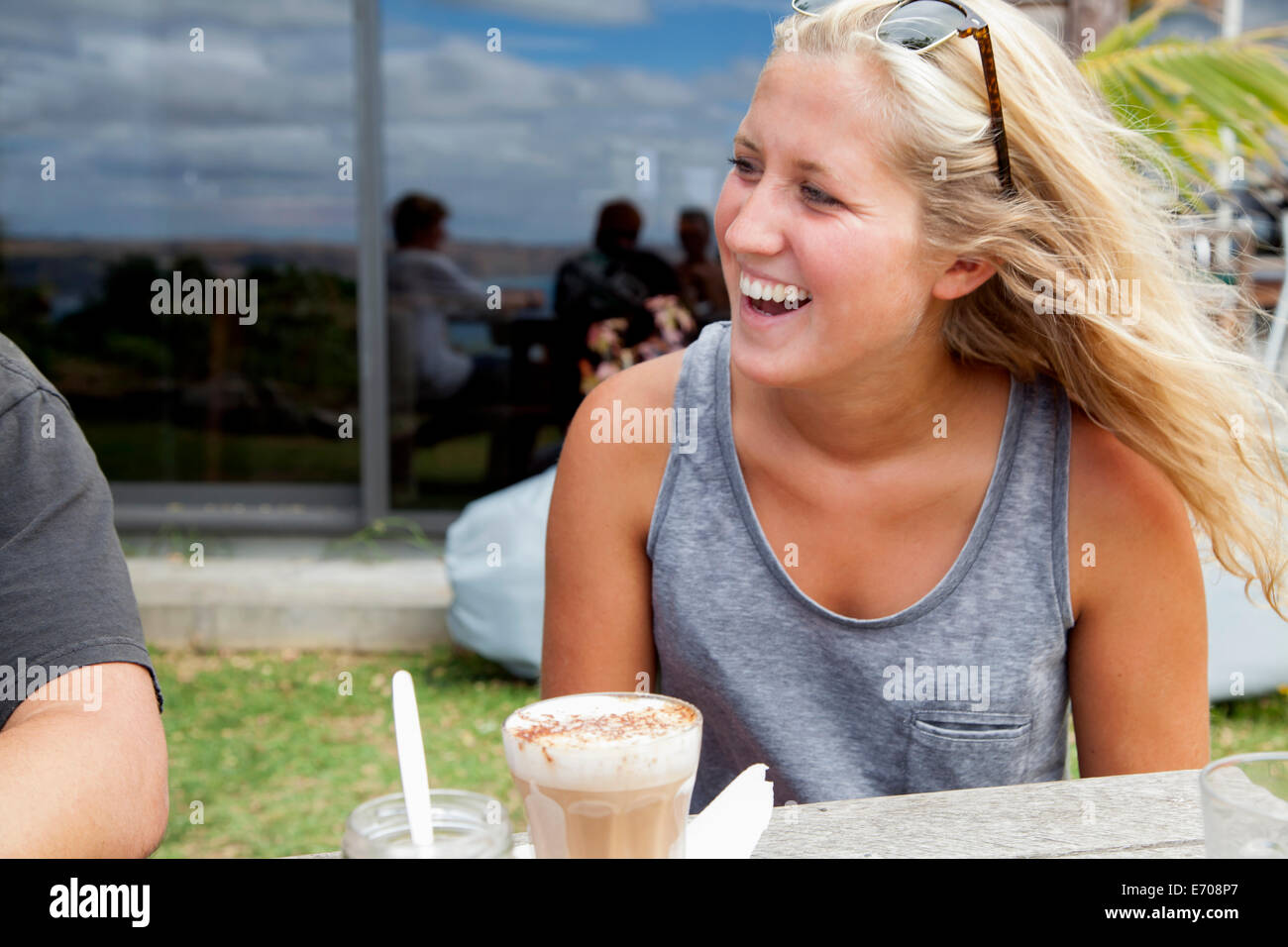 Young woman sitting at picnic bench drinking glass of latte Stock Photo