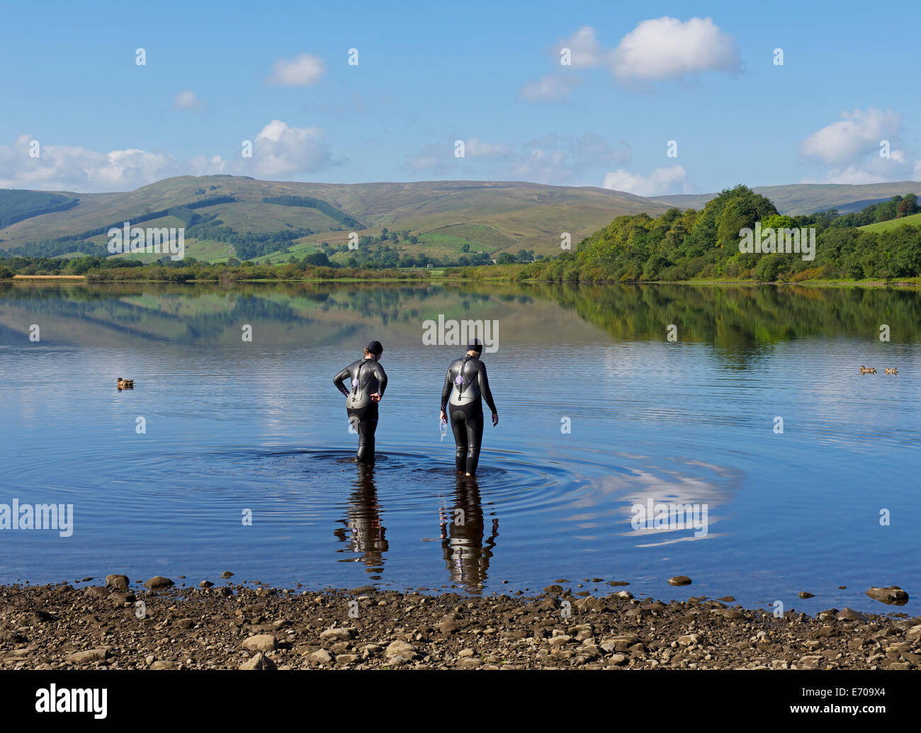 Two women in wetsuits wading into Semerwater, Yorkshire Dales National