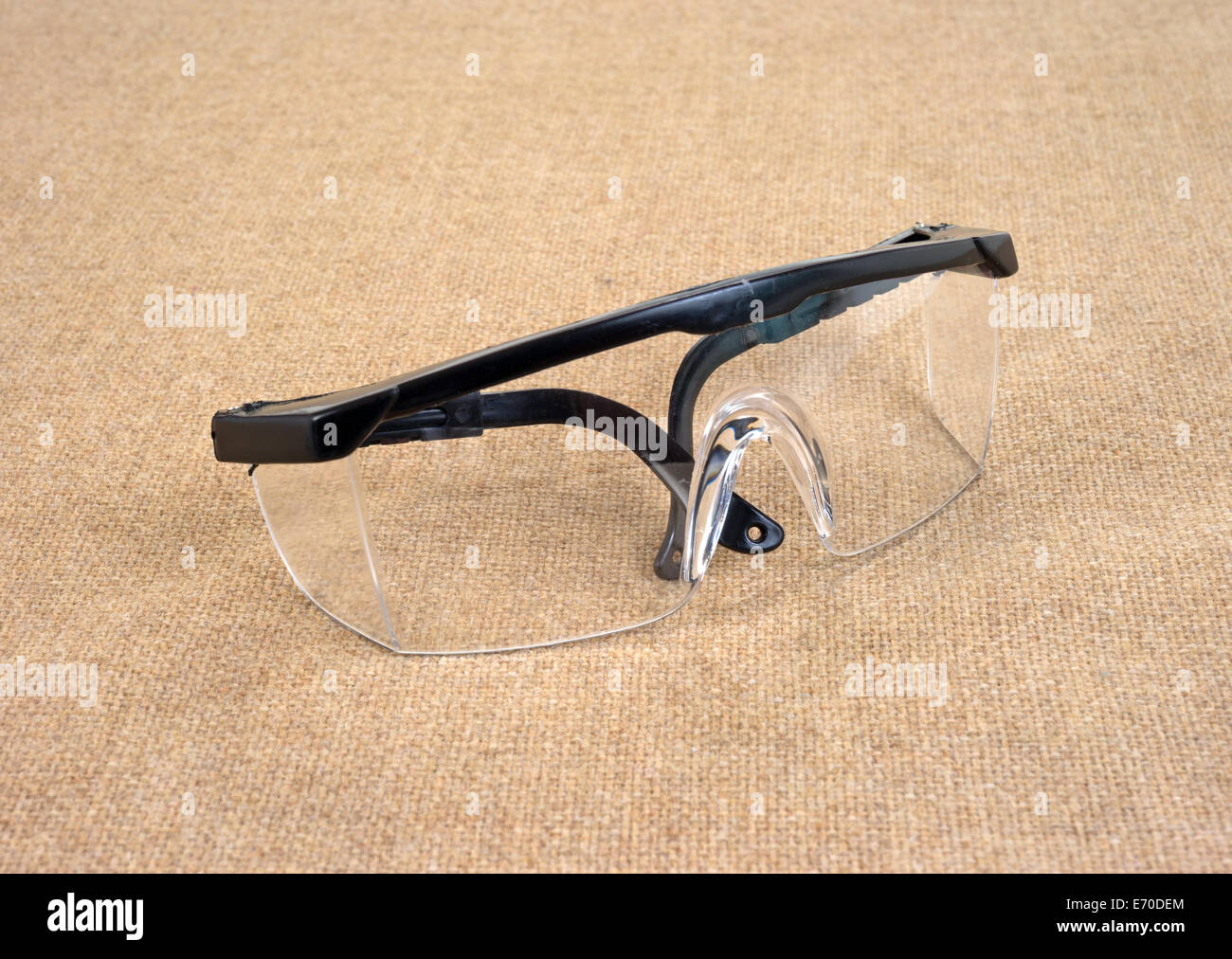 A pair of used safety glasses on a burlap background. Stock Photo