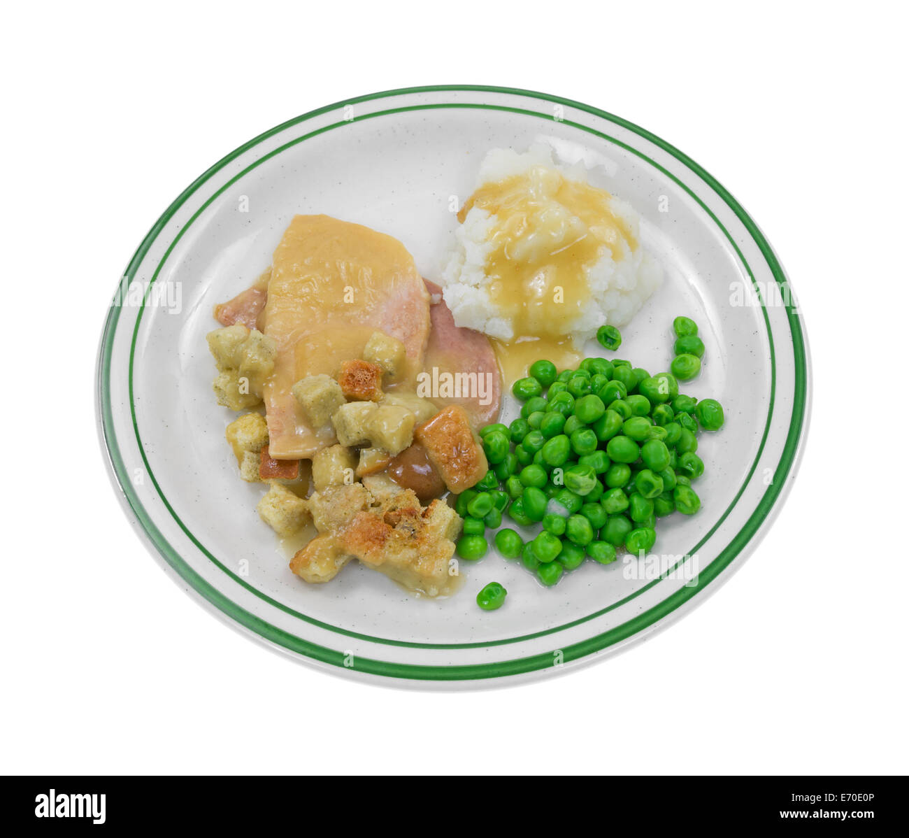 A sliced turkey in gravy with croutons, mashed potatoes and green peas on a plate. Stock Photo