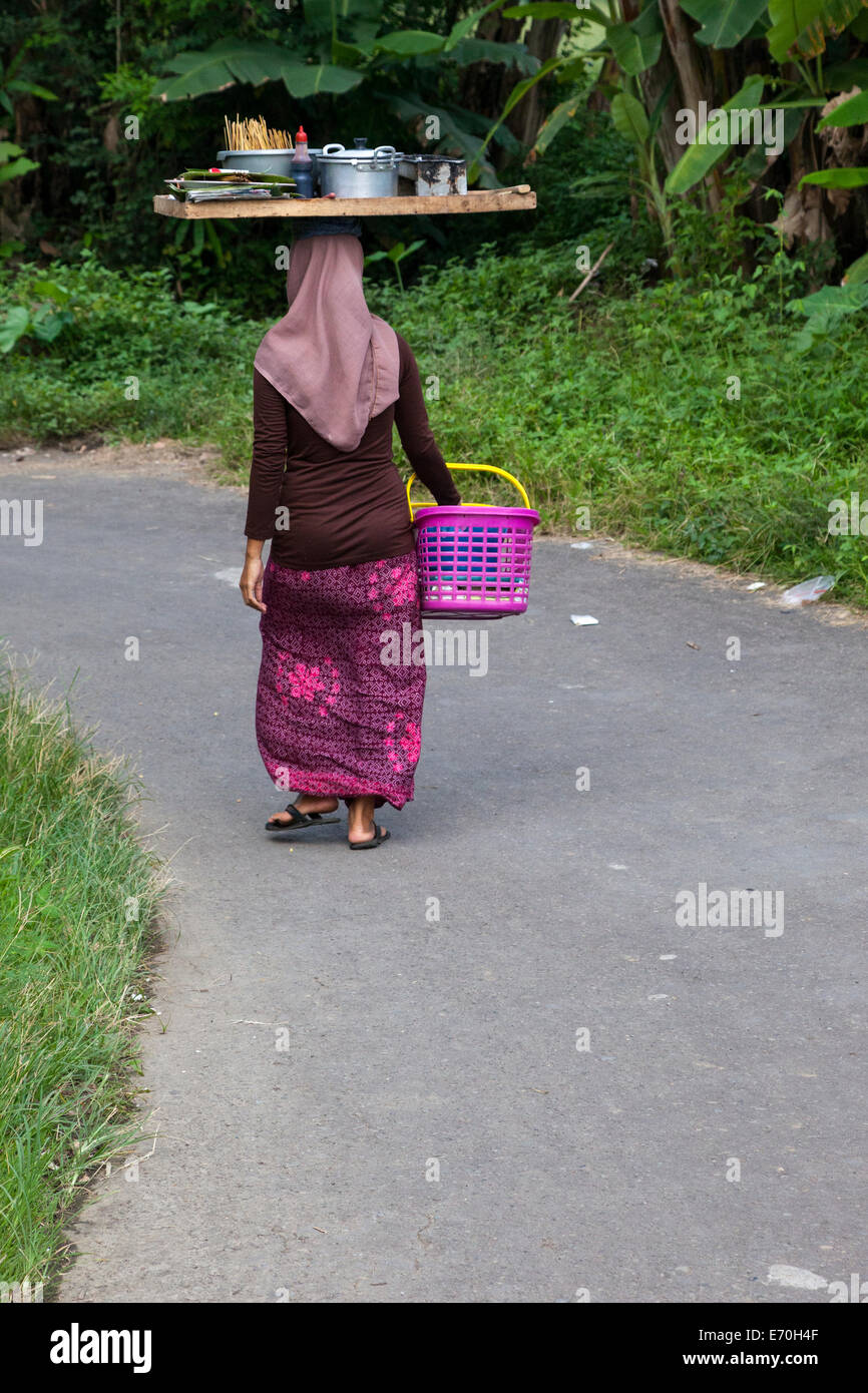 Borobudur, Java, Indonesia.  Village Woman Carrying Tray on Head. Stock Photo