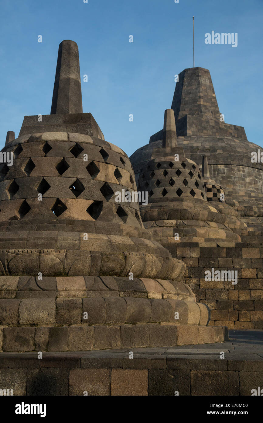 Borobudur, Java, Indonesia.  Three Small Stupas, Topmost Stupa in Background.  Symbolic Openings. Stock Photo