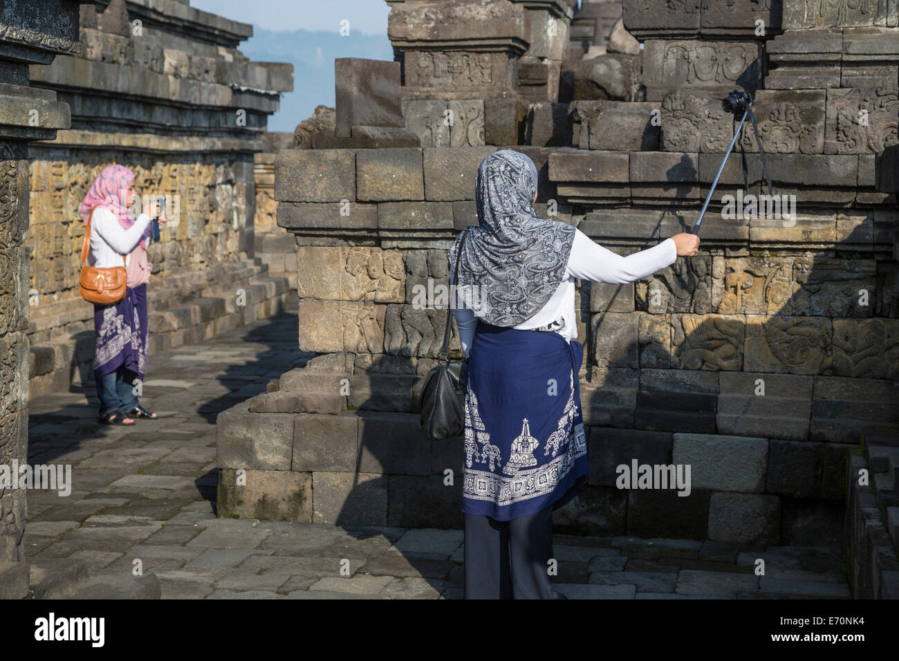 Borobudur, Java, Indonesia.  Two Young Indonesian Women Photographing the Temple one using an extension pole. Stock Photo