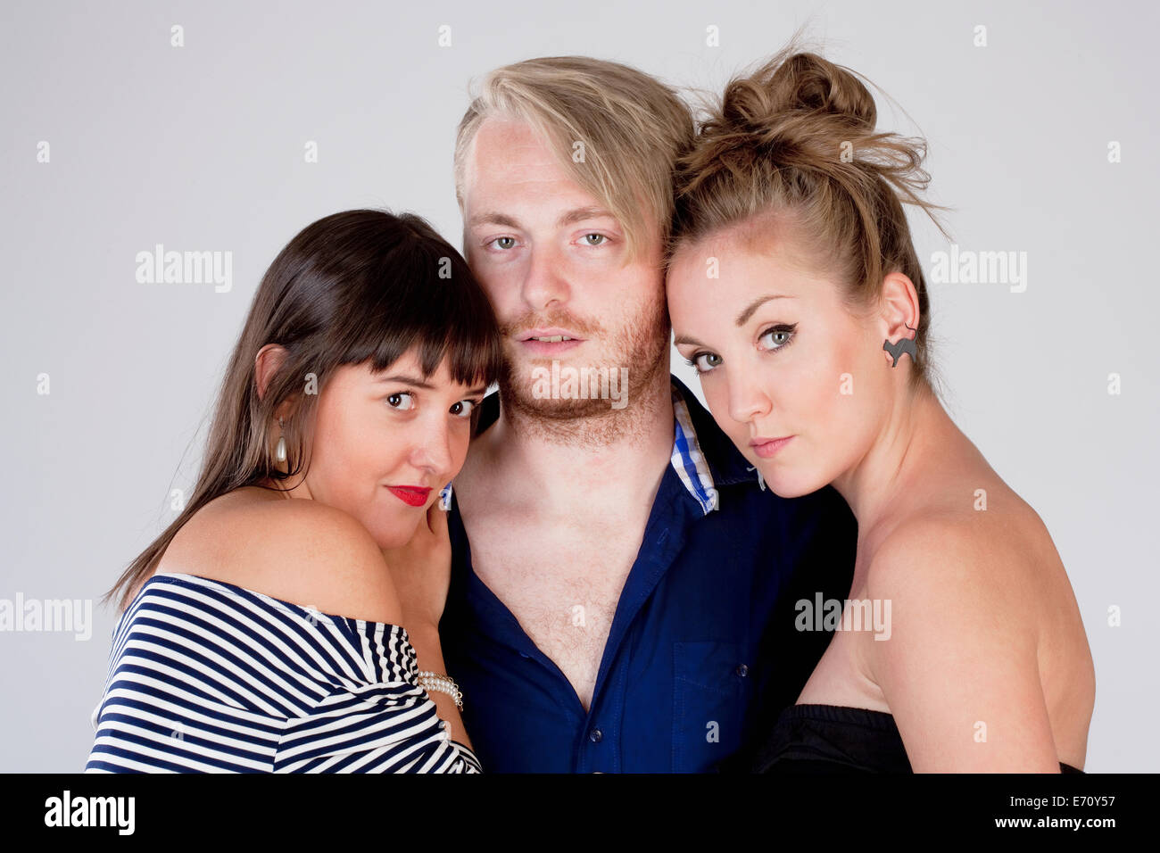 Two Young Female Friends Embracing a Man - Isolated on Gray Stock Photo