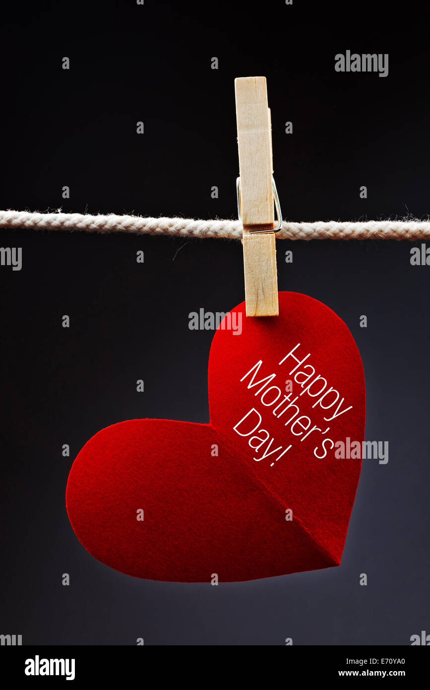 Happy Mother's Day printed on red heart attached to rope with clothes pins. Stock Photo