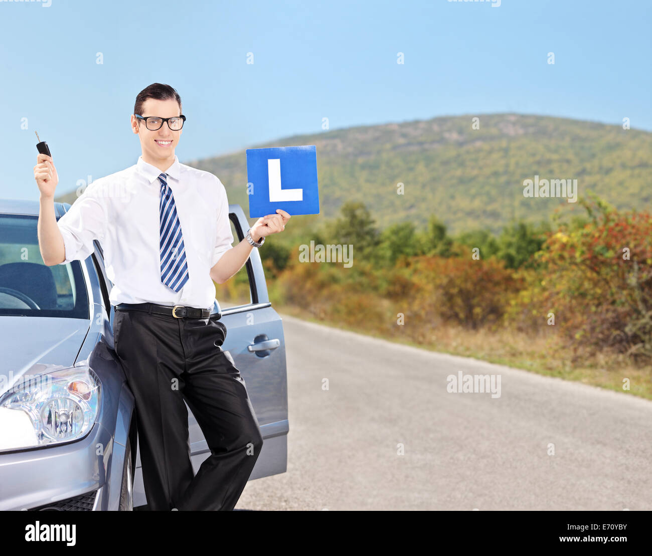 Male driver holding l sign and a car key on an open road shot with tilt and shift lens Stock Photo