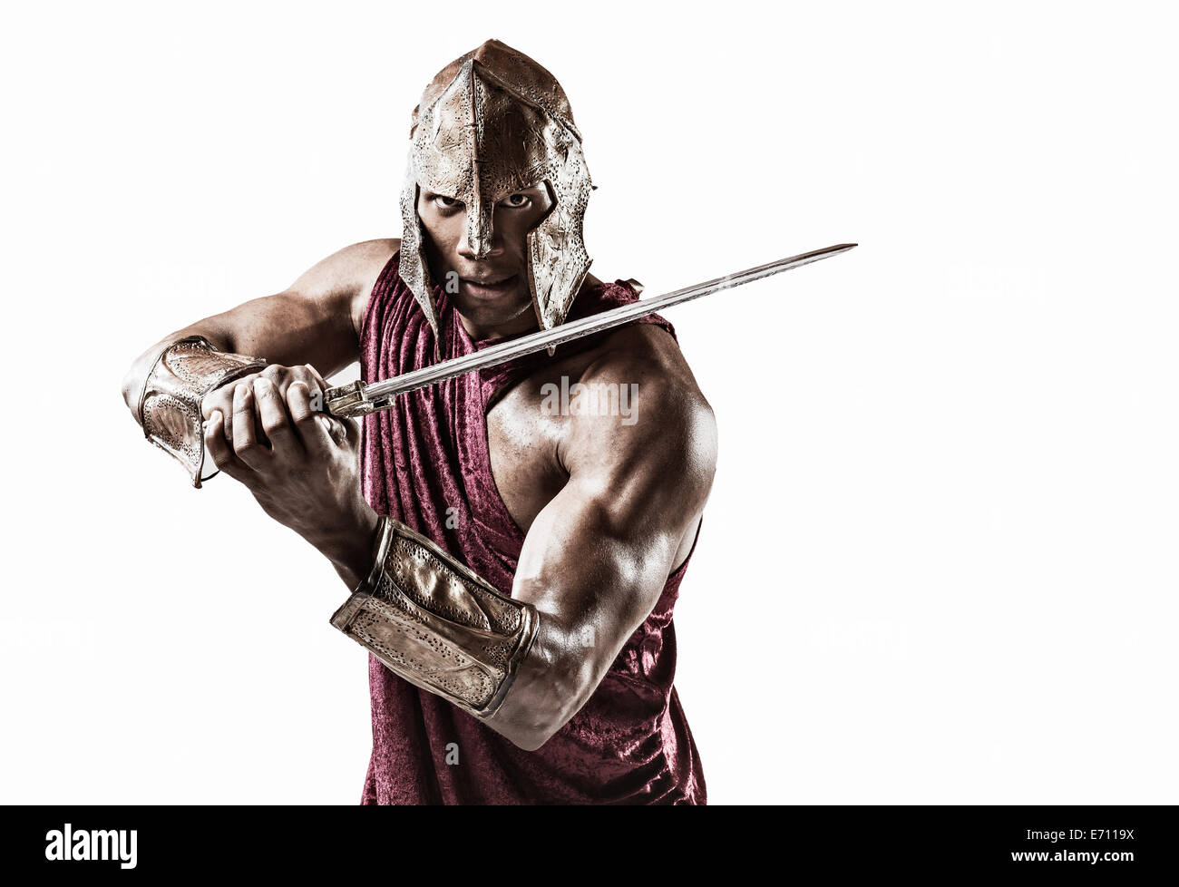 Studio portrait of muscular young man dressed as gladiator with helmet and sword Stock Photo