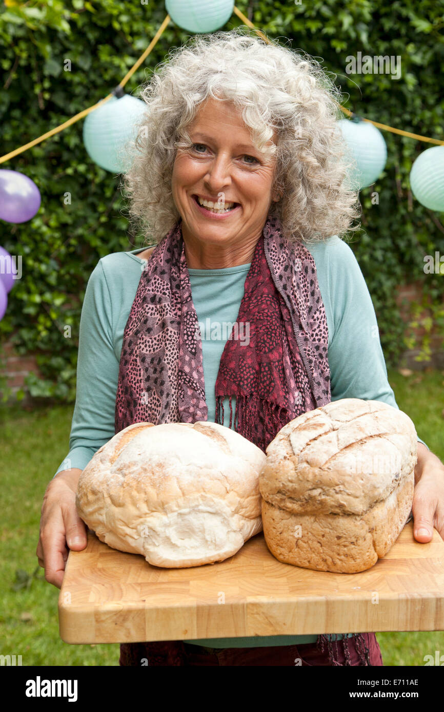 Portrait of mature woman with loaves of bread at garden party Stock Photo