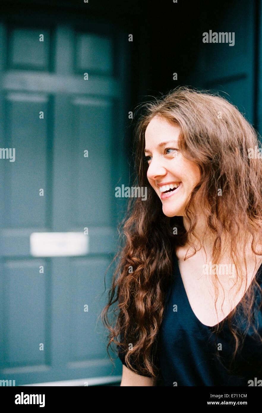 A woman smiling standing at an open doorway Stock Photo - Alamy