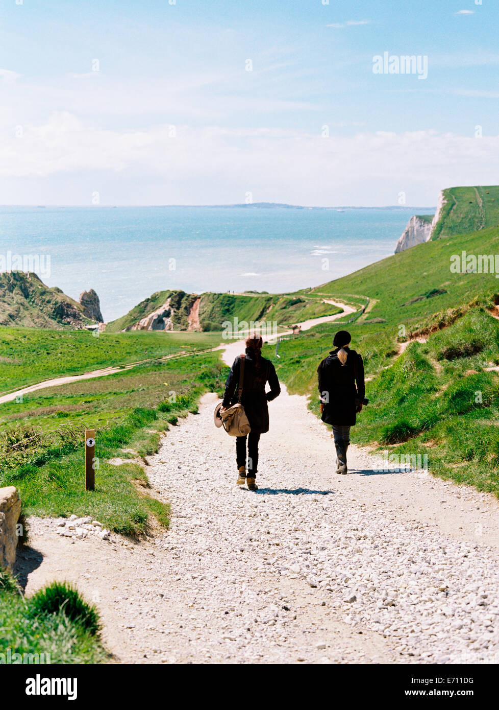 Two women walking on a coastal footpath along cliffs. Stock Photo