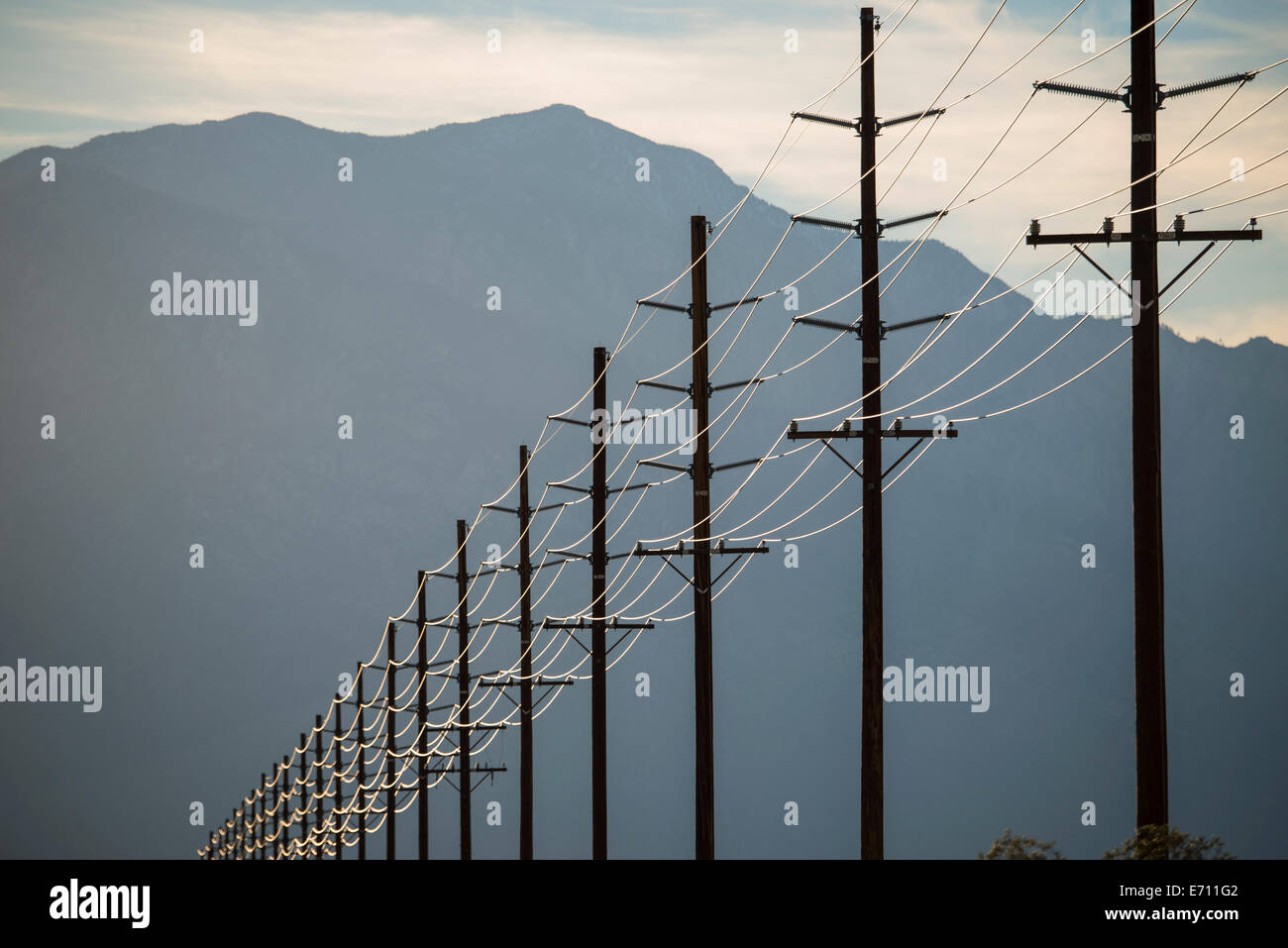 Power lines in rows across the landscape, against a mountain and sunset
