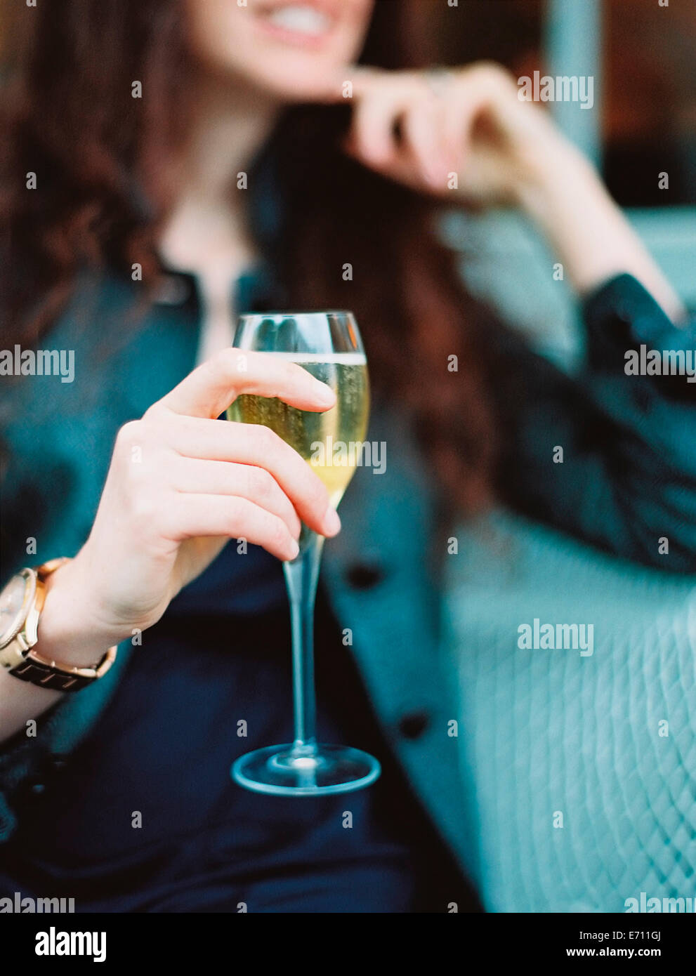 A woman holding a glass of white wine with a long stem. Stock Photo