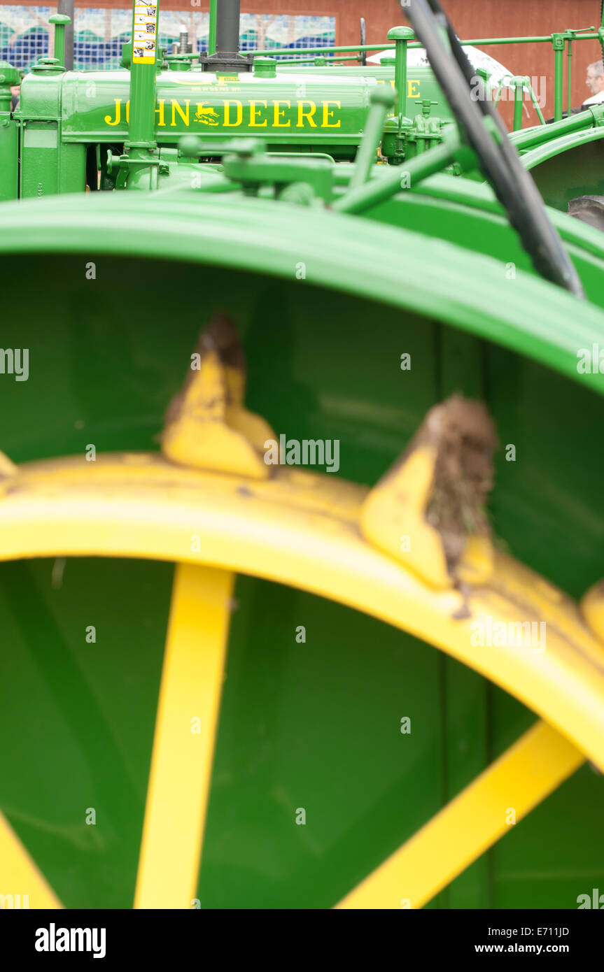 The rear wheel of a John Deere tractor on display among others at a John Deere tractor expo. Stock Photo