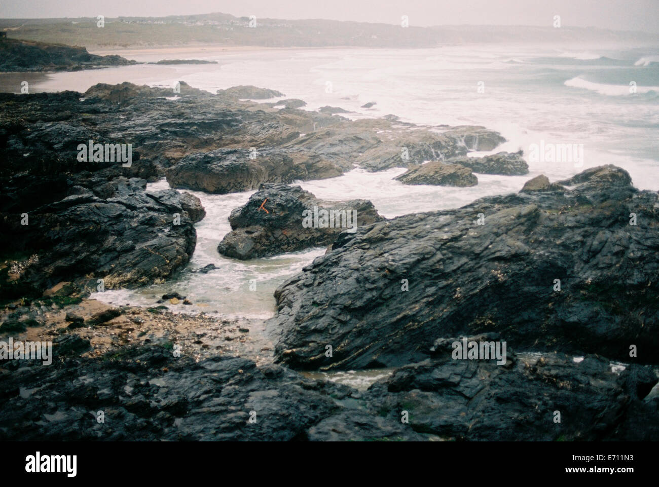 Rocks on the beach by the sea. Waves breaking and mist rising. Stock Photo