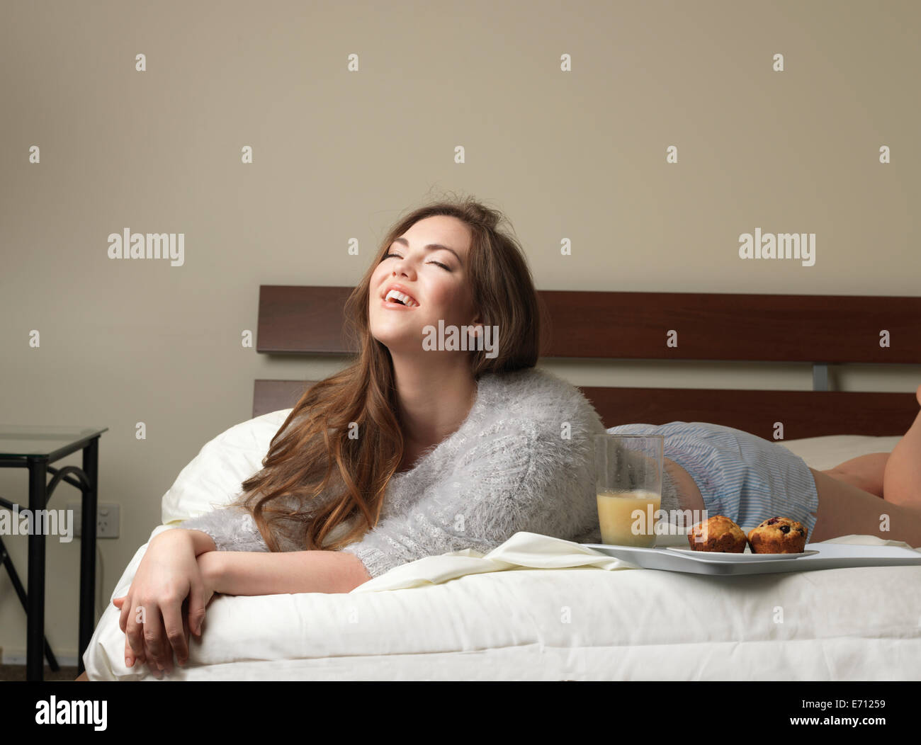 Beautiful young woman laughing on hotel bed Stock Photo