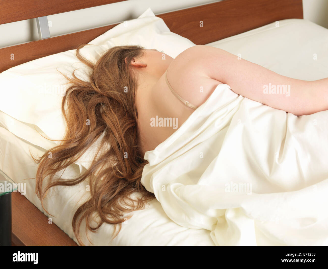 Rear view of young woman sleeping in bed Stock Photo