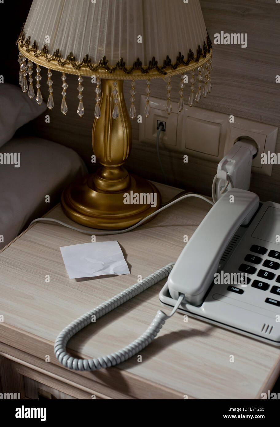 Landline phone and blank note on hotel room bedside table Stock Photo