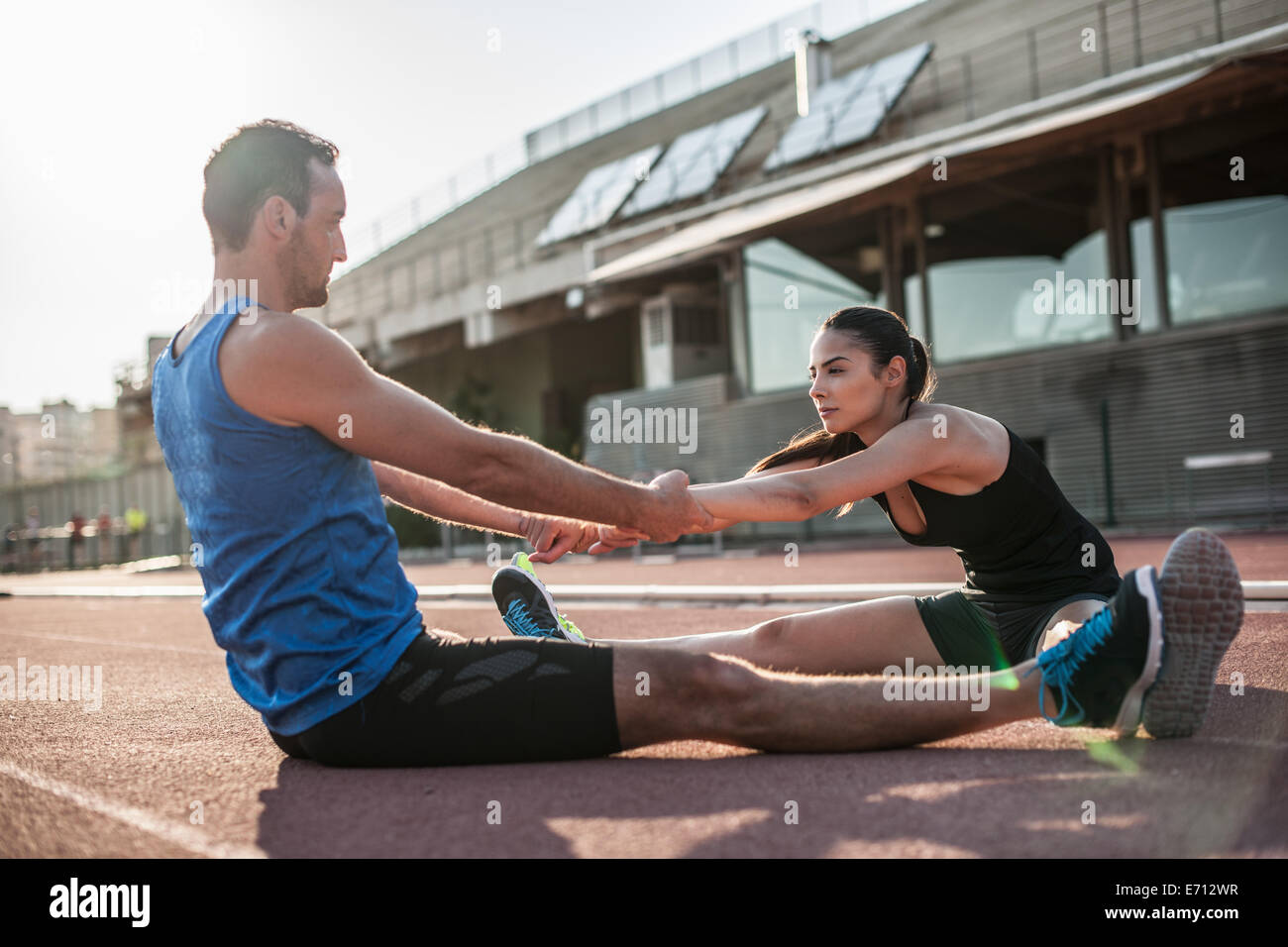 Man and woman sitting on floor stretching Stock Photo