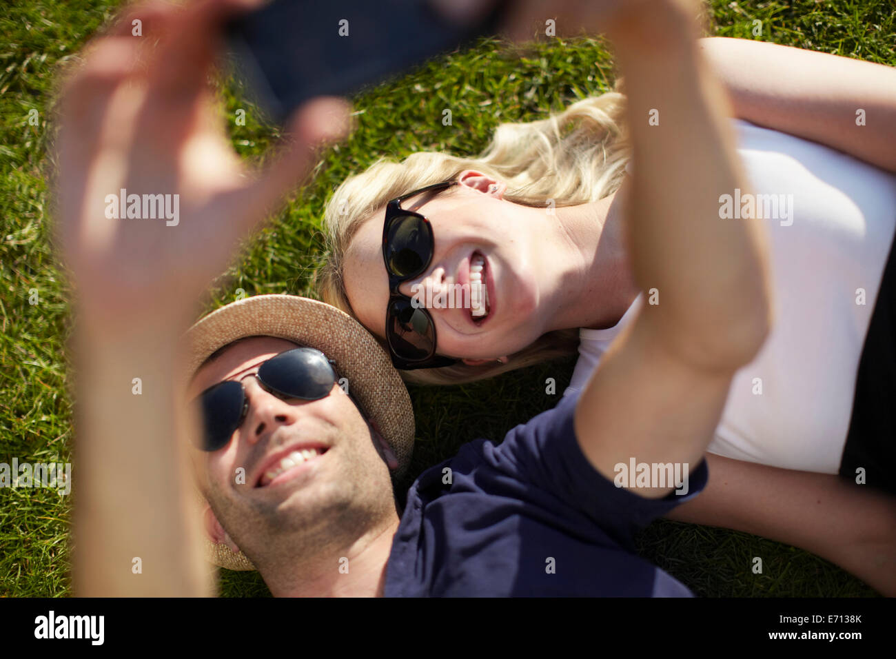 Couple lying in park taking selfie on smartphone Stock Photo - Alamy