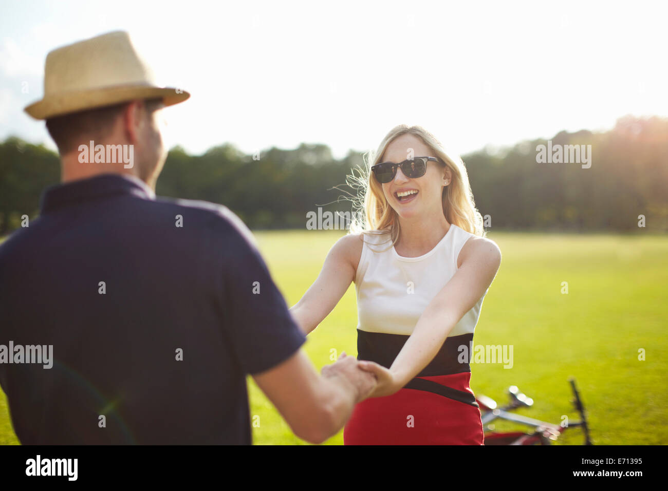 Couple holding hands and swirling each other around in park Stock Photo