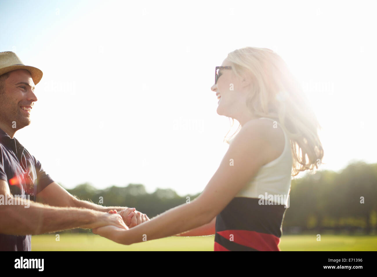 Couple swirling each other around in park Stock Photo