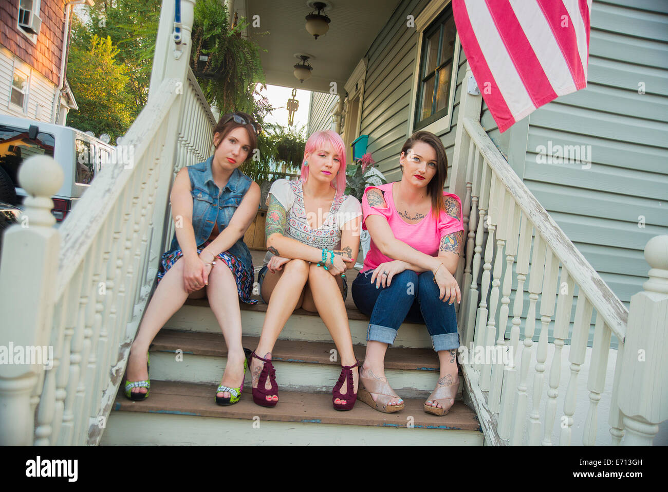 Portrait of young female friends sitting on porch steps Stock Photo