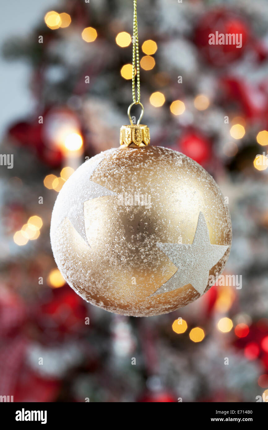 Golden Christmas bauble with white stars hanging in front of blurred flares Stock Photo