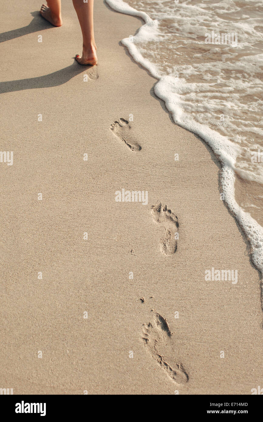 Indonesia, Gili Islands, woman walking on the beach leaving footprints, partial view Stock Photo