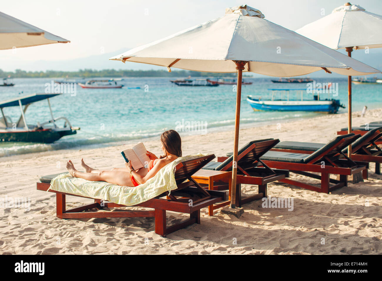 Indonesia, Gili Islands, woman lying on a beach chair reading a book Stock Photo