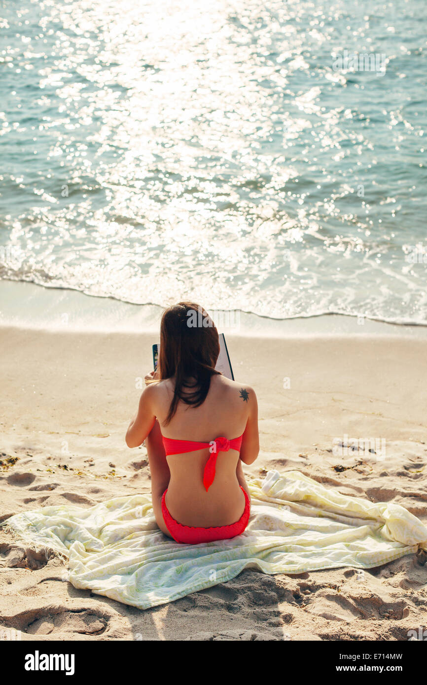 Indonesia, Gili Islands, woman reading a book on the beach, back view Stock Photo