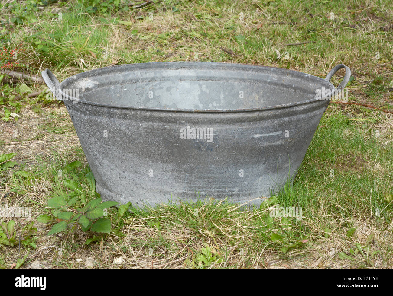 Empty tin bath standing on rough grass and weeds Stock Photo