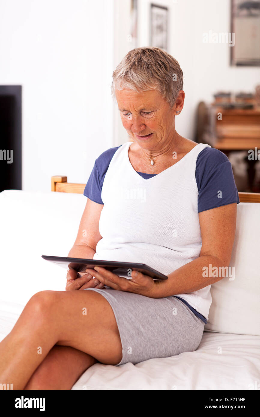 Senior woman sitting on couch using digital tablet Stock Photo - Alamy