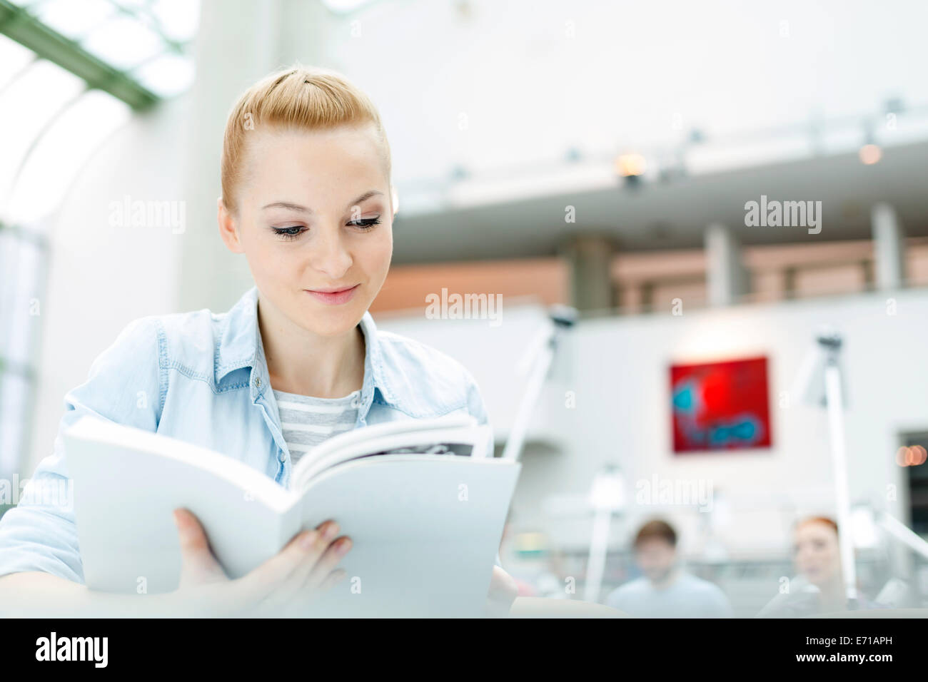 Student in a university library reading book Stock Photo - Alamy
