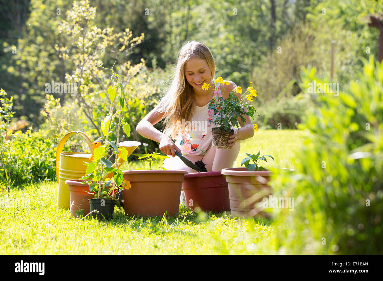 Smiling teenage girl repotting plants in the garden Stock Photo