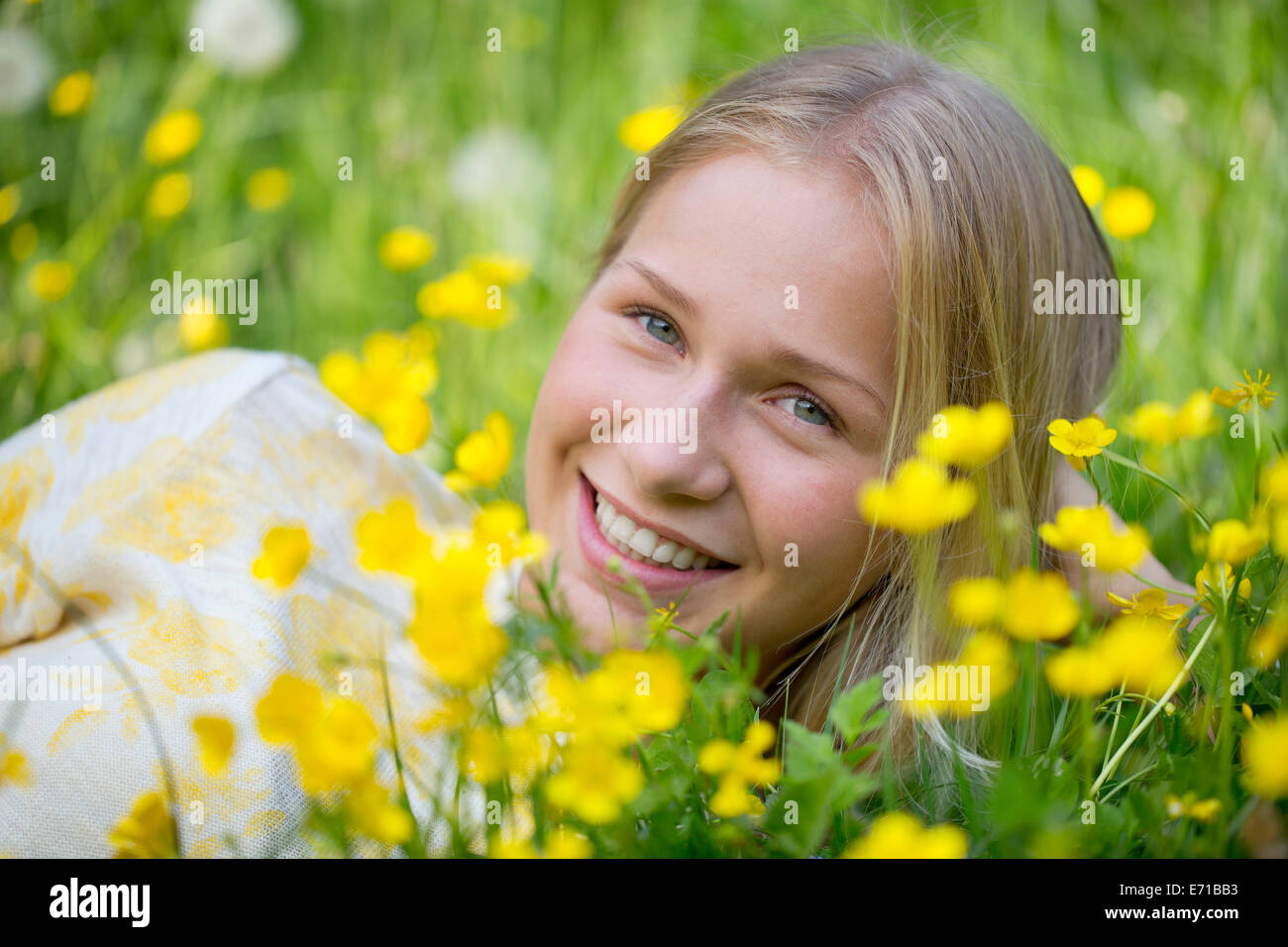 Portrait of smiling teenage girl lying on a flower meadow Stock Photo