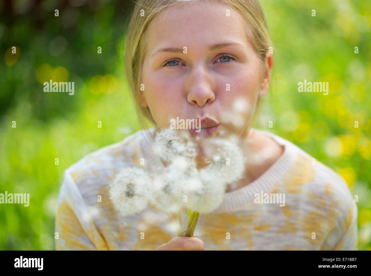 Portrait of teenage girl blowing blowballs on a flower meadow Stock Photo