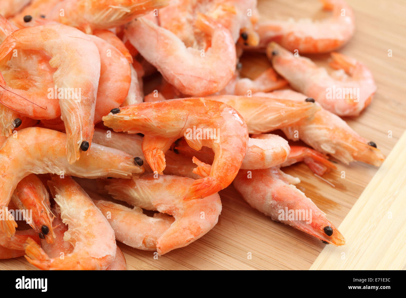 A pile of frozen shrimps on a cutting board. Closeup. Stock Photo
