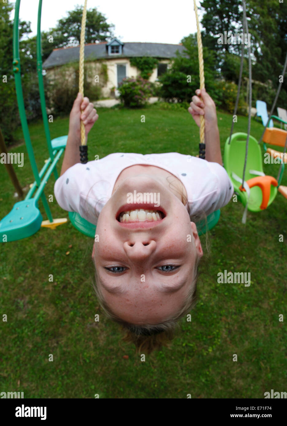 child on a swing swinging upside down Stock Photo
