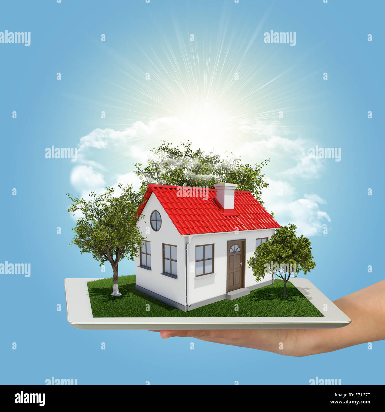 Human hand holding tablet pc with small house and trees Stock Photo