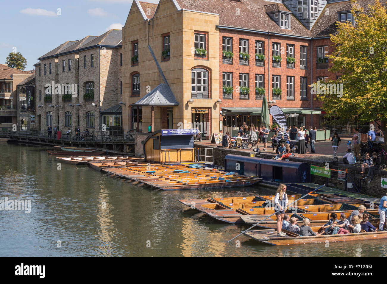 A row of punt boats waiting on the River Cam in Cambridge with crowds gathering in the background Stock Photo