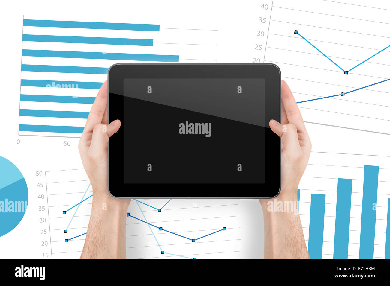 Hand holding digital tablet with blank screen and financial graphics ...